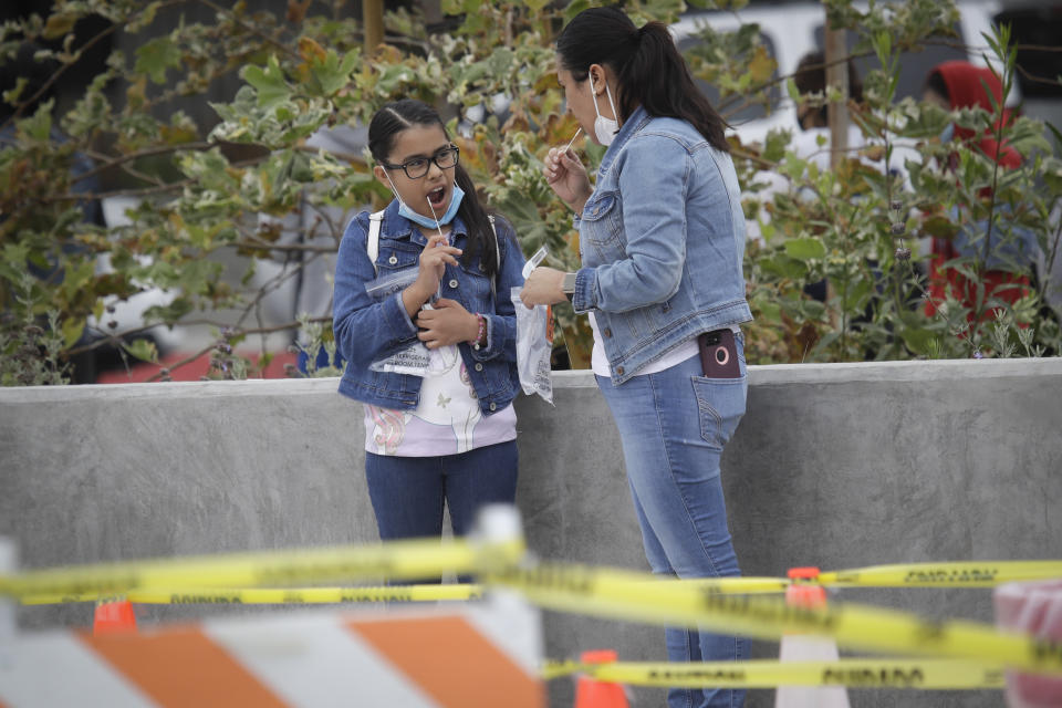 FILE - In this July 22, 2020, file photo, a woman and girl take a coronavirus test together in Los Angeles. California has stopped updating a list of counties facing more restrictions on businesses and schools after a problem in the state's coronavirus testing database has led to an undercount. (AP Photo/Marcio Jose Sanchez, File)