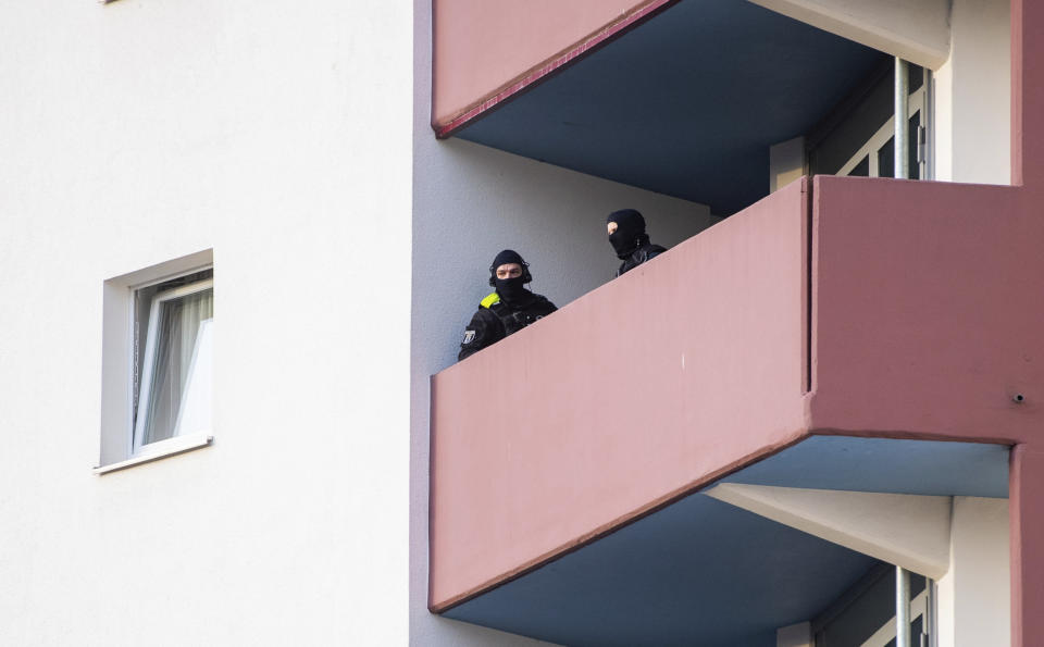 Police officers stand on a balcony of an apartment building during raids against an Islamist network at the Maerkische Viertel neighborhood in Berlin, Thursday, Feb. 25, 2021. Police searched the apartments of several alleged supporters of a banned Islamic extremist organization in the German capital. (Christophe Gateau/dpa via AP)