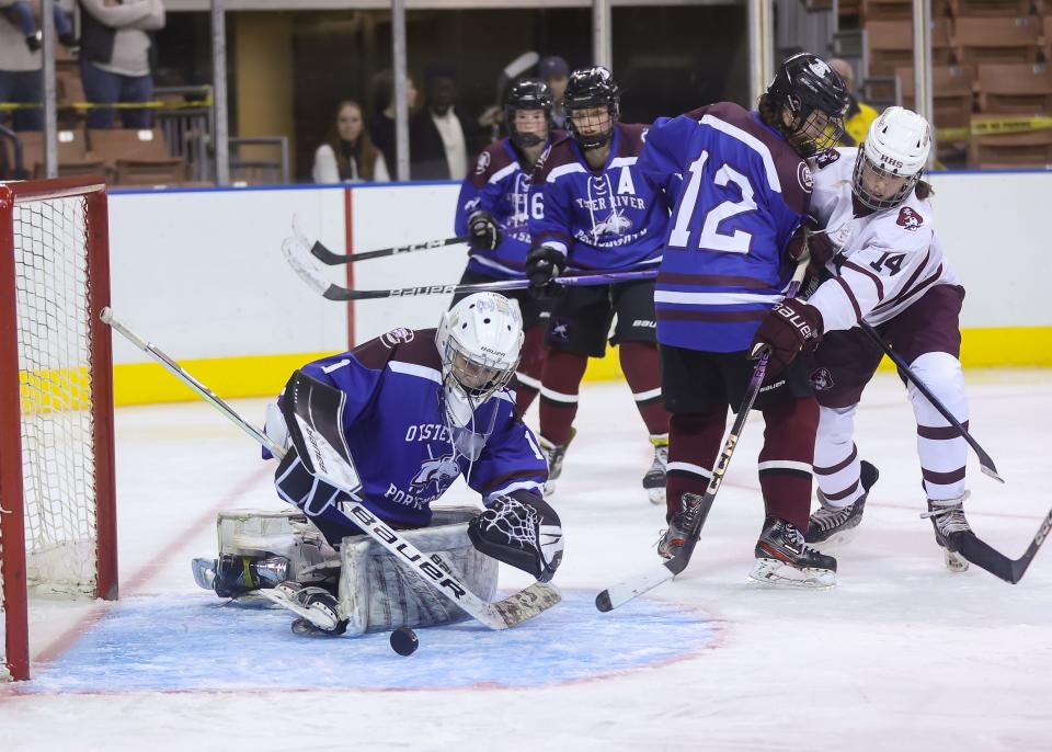 Oyster River/Portsmouth sophomore goalie Sage Bussiere fends off the puck on a shot by Hanover's Julia Lawe as teammate Hannah Henderson (12) defends during Saturday's Division I girls hockey championship game at Southern New Hampshire University Arena in Manchester. Bussiere had 20 saves in the game.