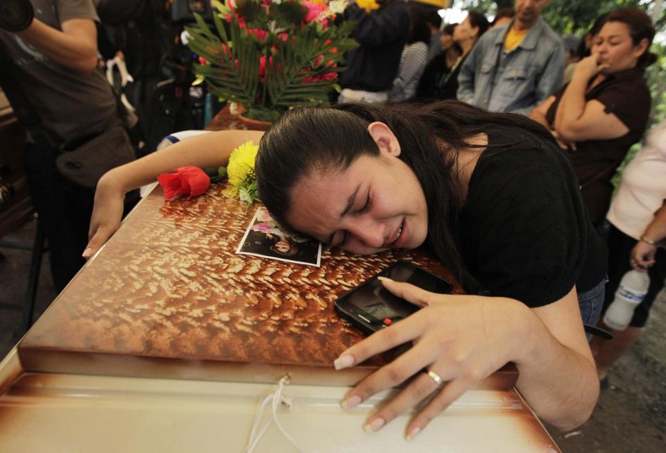 A friend lies over the coffin of Maria Jose Alvarado during a wake for Maria Jose and her sister Sofia outside their home in Santa Barbara November 20, 2014. The Honduran beauty queen has been found shot dead in a suspected crime of passion just days before she was due to compete in the Miss World pageant in London, police said on Wednesday. The bodies of Maria Jose, 19, and her sister Sofia, 23, were found buried near a river in the mountainous region of Santa Barbara in western Honduras, said Leandro Osorio, head of the criminal investigation unit. REUTERS/Jorge Cabrera (HONDURAS - Tags: CRIME LAW CIVIL UNREST ENTERTAINMENT)