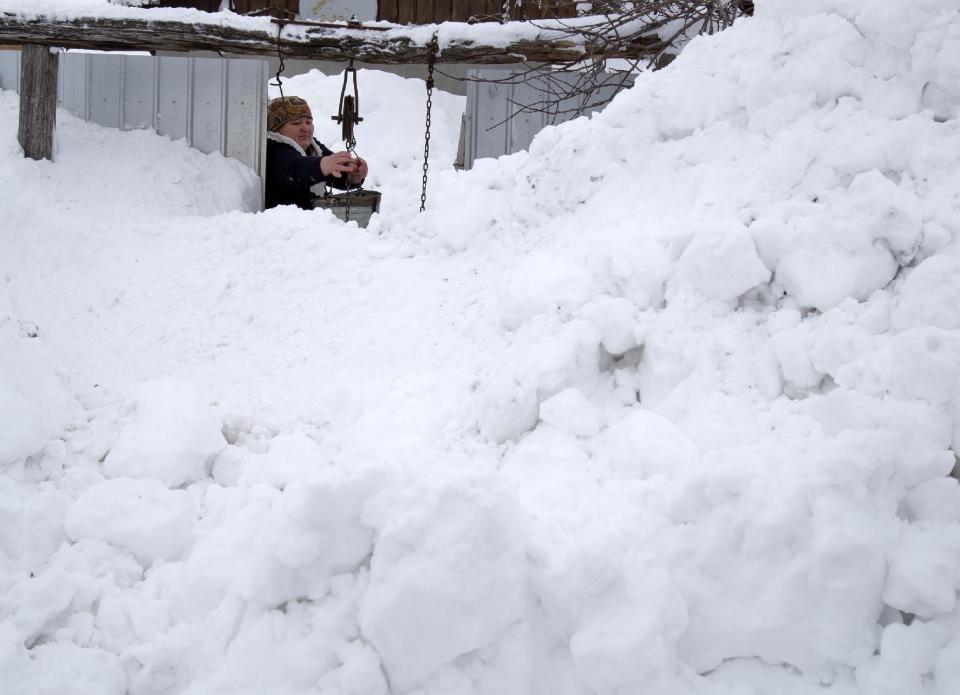 A woman gets water from a well in a garden in the village of Smeeni, Romania, Tuesday, Jan. 28, 2014. Snow storms are forecast for the coming days in the already affected southeastern regions of Romania in which road and rail traffic were badly disrupted. (AP Photo/Vadim Ghirda)