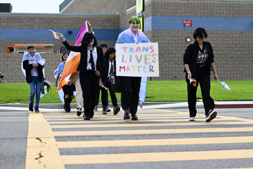 FILE - Students carrying pride flags and transgender flags leave Great Oak High School in Temecula, Calif., Friday, Sept. 22, 2023, after walking out of the school in protest of the Temecula school district policy requiring parents to be notified if their child identifies as transgender. The rights of LGBTQ+ people continue to be in flux across the U.S. with a new flurry of developments. (Anjali Sharif-Paul/The Orange County Register via AP, File)