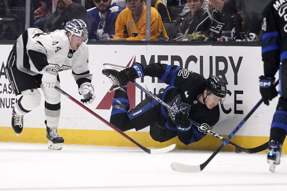 Toronto Maple Leafs defenseman Filip Kral, right, falls as he tries to pass the puck while under pressure from Los Angeles Kings defenseman Mikey Anderson during the second period of an NHL hockey game Saturday, Oct. 29, 2022, in Los Angeles. (AP Photo/Mark J. Terrill)