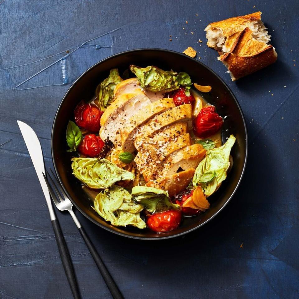 sautéed chicken and tomatoes with roasted artichokes in a black bowl