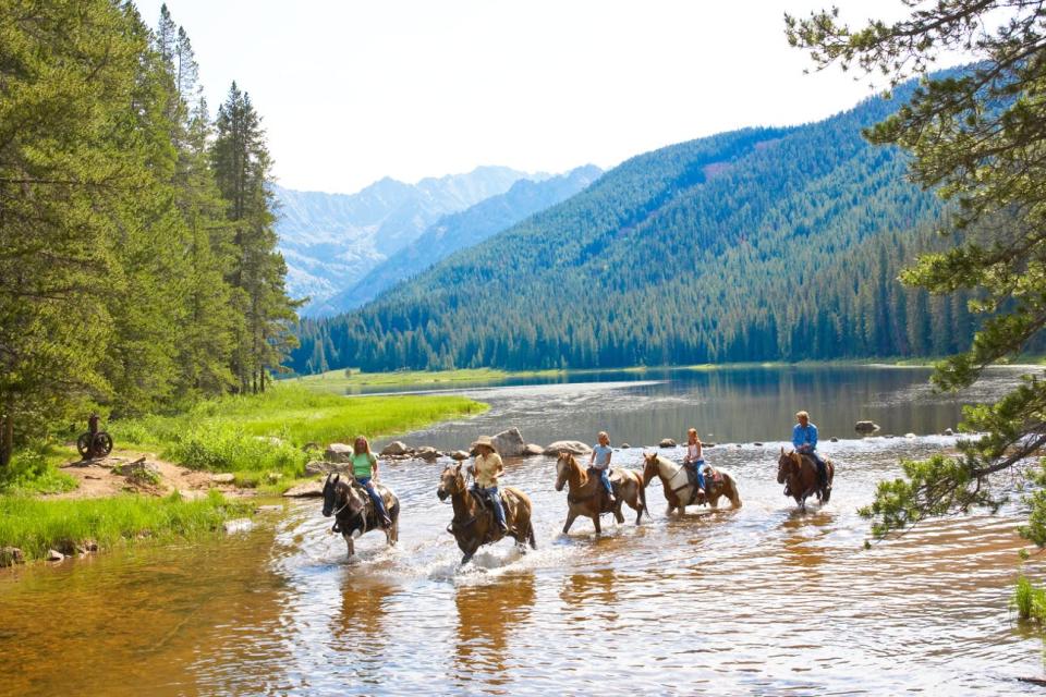 A group of riders in Vail, Colorado ford a river on horseback