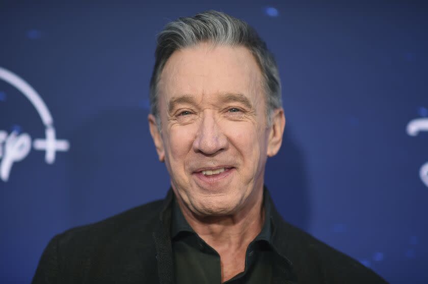 A man with short gray hair smiling in a black collared shirt