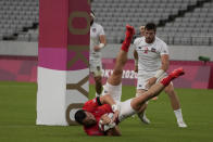 Britain's Alex Davis scores a try as Brett Thompson of the United States looks on, in their men's rugby sevens quarterfinal match at the 2020 Summer Olympics, Tuesday, July 27, 2021 in Tokyo, Japan. (AP Photo/Shuji Kajiyama)