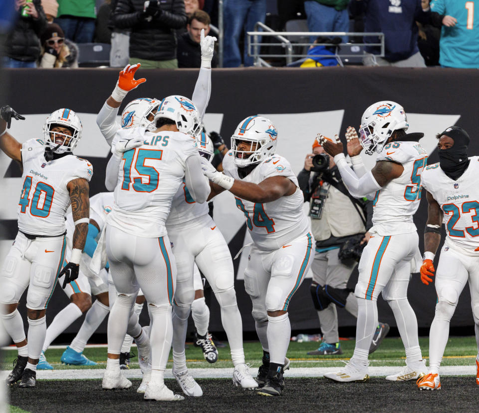 Miami Dolphins safety Jevon Holland (8) celeb rates with teammates after scoring on intercepted pass during second quarter of an NFL football game against the New York Jets, Friday, Nov. 24, 2023, in East Rutherford, N.J. (David Santiago/Miami Herald via AP)