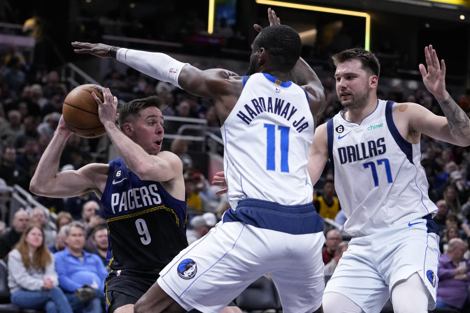 Indiana Pacers guard T.J. McConnell (9) is stopped as he drives by Dallas Mavericks forward Tim Hardaway Jr. (11) and guard Luka Doncic (77) during the second half of an NBA basketball game in Indianapolis, Monday, March 27, 2023. The Mavericks defeated the Pacers 127-104. (AP Photo/Michael Conroy)