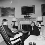 President John F. Kennedy (sitting in rocking chair) meets with publisher of the New York Journal-American newspaper, Kingsbury Smith. Oval Office, White House, Washington, D.C. (JFK Presidential Library)