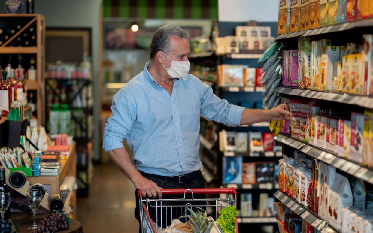 Man grocery shopping at the supermarket wearing a face mask