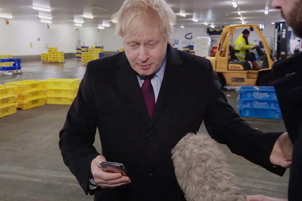 Prime Minister Boris Johnson looking at a photograph of a four-year-old boy with suspected pneumonia having to sleep on the floor in a hospital (PA)