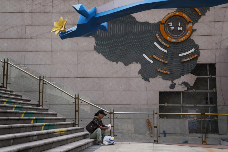 FILE - A woman sorts out her groceries near a map showing partially damaged Evergrande development projects in China, at an Evergrande city plaza in Beijing on Sept. 18, 2023. (AP Photo/Andy Wong, File)