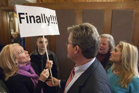 Gina Macdonald-Page (L) holds up a sign for Ted Kennedy Jr. (C), son of the late Democratic Massachusetts Senator Edward M. Kennedy, after he declared his candidacy for a seat in the Connecticut Senate, in Branford, Connecticut April 8, 2014. REUTERS/Michelle McLoughlin