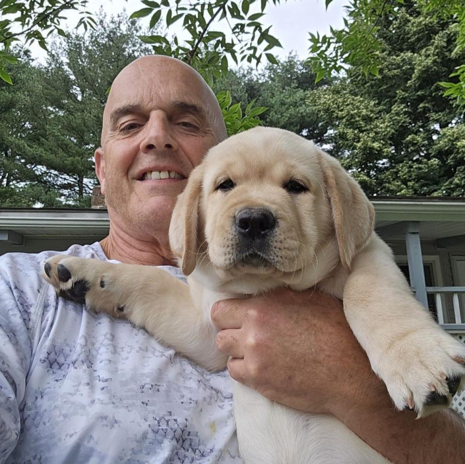 Steve O'Neil holds up the Hampton Police Department's new comfort dog, a 9-week-old Labrador.