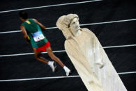 An athlete runs past a statue during his last lap in men's marathon of Athens Olympic Games August 29, 2004. REUTERS/Damir Sagolj