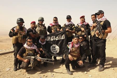 Kurdish Peshmerga fighters pose with an Islamic State flag, which they pulled down after capturing Mount Batnaya, near Zummar September 20, 2014. REUTERS/Ari Jalal