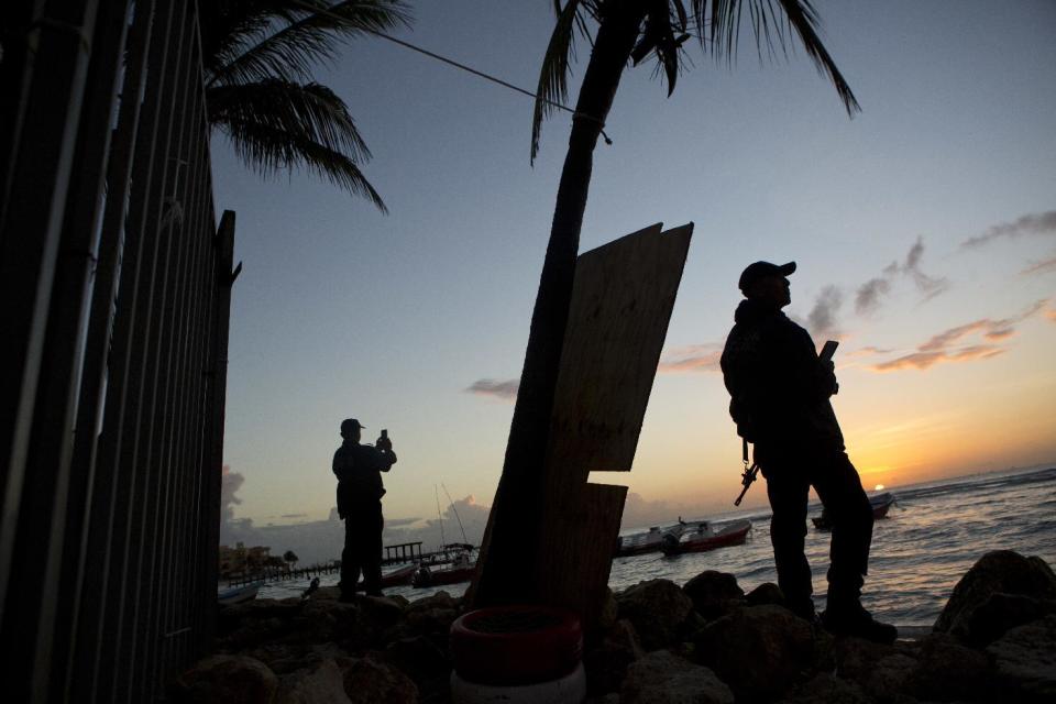 In this Jan. 17, 2017 photo, municipal police watch the sunrise as they stand guard on the beach in front of the Blue Parrot club, a day after a deadly early morning shooting, in Playa del Carmen, Mexico. Mexican authorities said Tuesday they are investigating whether extortion, street-level drug sales or a murder plot was the motive behind a shooting at an electronic music festival at a Caribbean resort town that left three foreigners and two Mexicans dead.(AP Photo/Rebecca Blackwell)