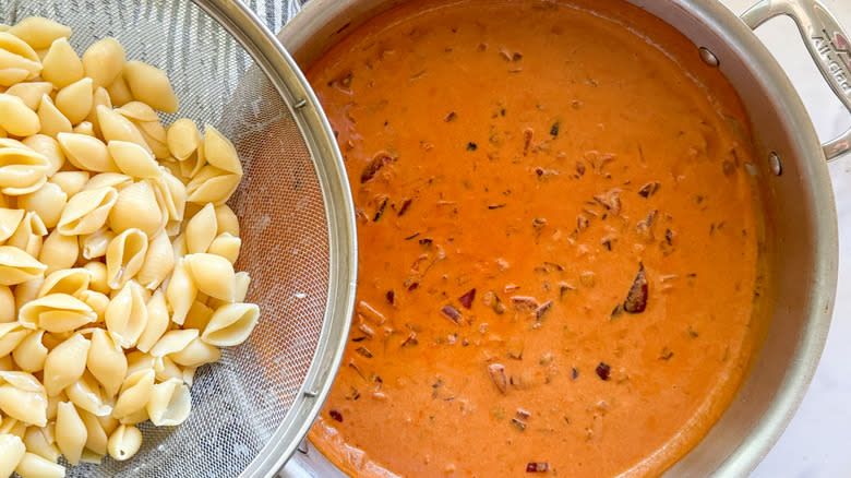 adding cooked pasta to pan of vodka sauce