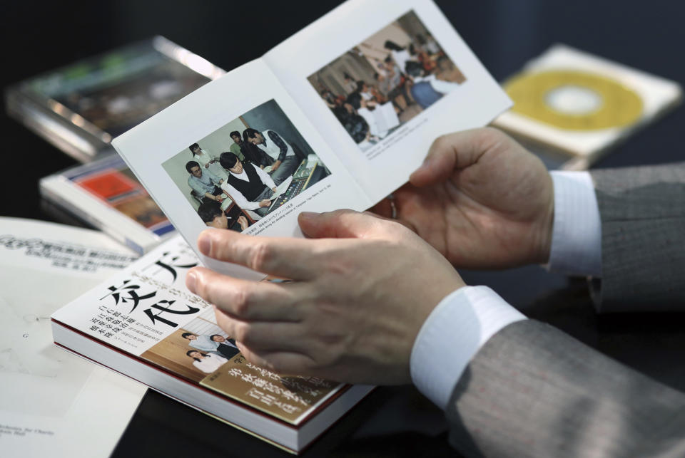 In this March 9, 2019, photo, Toshio Shiraishi, violoncello of amateur Shunyukai Symphony Orchestra shows a booklet of their CD including a picture of Crown Prince Naruhito during an interview with The Associated Press in Tokyo. Shiraishi is a long time school and orchestra friend of Naruhito. (AP Photo/Eugene Hoshiko)