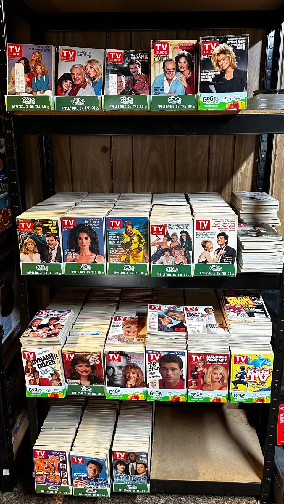 A shelf full of old TV Guide magazines, featuring various famous TV stars and iconic show covers from past decades, categorized and displayed neatly