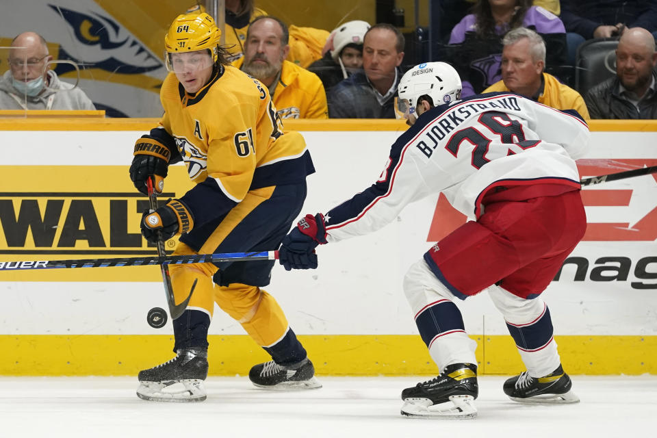 Nashville Predators center Mikael Granlund (64) and Columbus Blue Jackets right wing Oliver Bjorkstrand (28) battle for the puck in the second period of an NHL hockey game Tuesday, Nov. 30, 2021, in Nashville, Tenn. (AP Photo/Mark Humphrey)