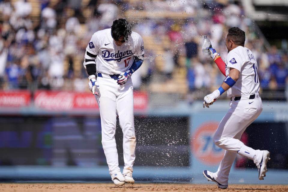 Los Angeles Dodgers' Shohei Ohtani, left, is sprayed with water by Miguel Rojas after Ohtani hit a walk-off single during the 10th inning of a baseball game against the Cincinnati Reds Sunday, May 19, 2024, in Los Angeles. The Dodgers won 3-2. (AP Photo/Mark J. Terrill)