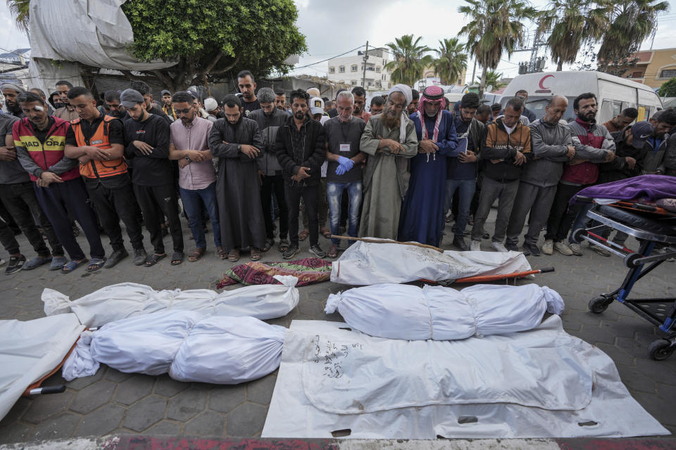 Palestinians pray by the bodies of people killed during Israeli airstrikes in the Gaza Strip, next to the morgue in Deir al Balah, Tuesday, May 14, 2024. (AP Photo/Abdel Kareem Hana)