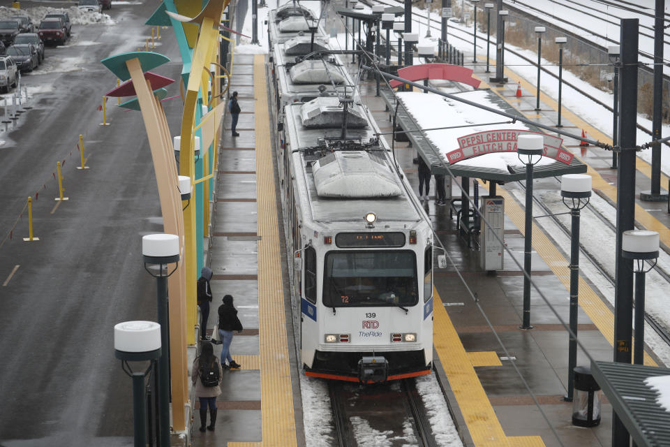 Bundled up against cold temperatures and light snow, passengers wait for a light rail train to pull up to a station, Wednesday, Feb. 12, 2020, in downtown Denver. Forecasters predict that the cold temperatures and snow will move out on to the plains and make way for warmer weather in the intermountain West in the weekend ahead. (AP Photo/David Zalubowski)