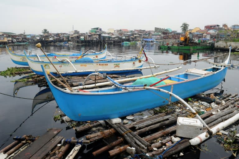 Fishing outrigger boats are anchored at the mouth of a river feeding Manila Bay on October 17, 2015, as the Philippine coast guard banned sailing due to nearby Typhoon Koppu