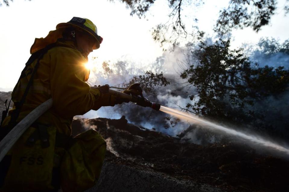A firefighter controls flames at a home set ablaze by the Skirball fire in Bel-Air.