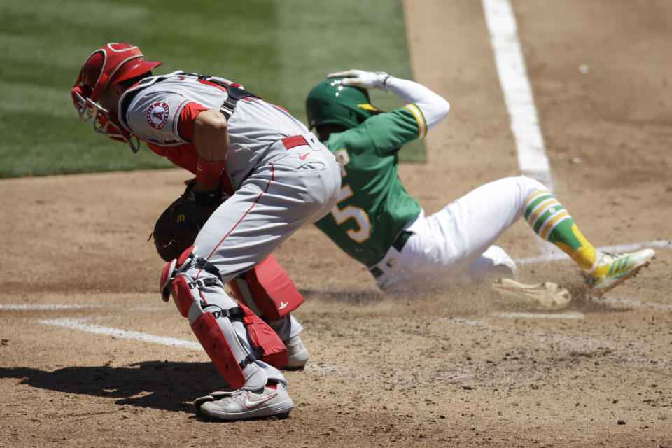 Oakland Athletics' Tony Kemp, right, scores past Los Angeles Angels catcher Jason Castro during the third inning of a baseball game Monday, July 27, 2020, in Oakland, Calif. (AP Photo/Ben Margot)