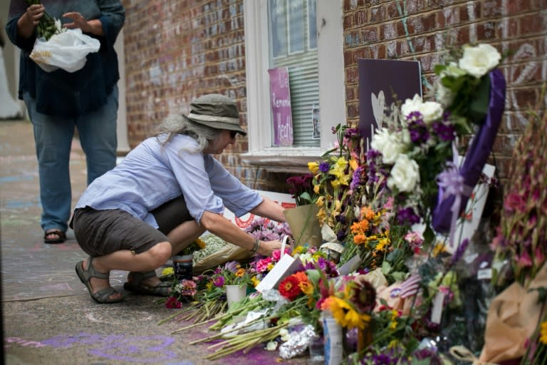 A woman places flowers on a makeshift memorial dedicated to Heather Heyer in downtown Charlottesville, Virginia, one year after the violent white nationalist rally where Heyer was killed and dozens of others were injured