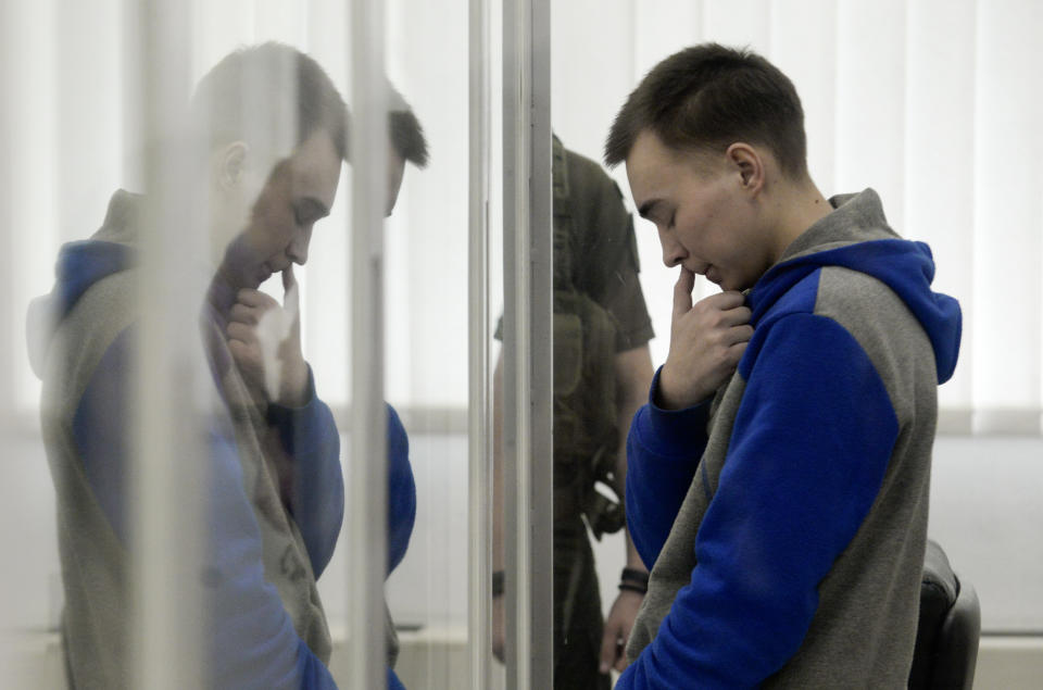 FILE - Russian army Sgt. Vadim Shishimarin, 21, is seen behind a glass during a court hearing in Kyiv, Ukraine, Monday, July 25, 2022. The 21-year-old tank commander was the first Russian tried on war crimes charges. He surrendered in March and pleaded guilty in a Kyiv courtroom in May to shooting a 62-year-old Ukrainian civilian in the head. Ukrainian prosecutors, however, have not yet been able to charge Shishimarin's commanders or those who oversaw him. (AP Photo/Danylo Antoniuk)