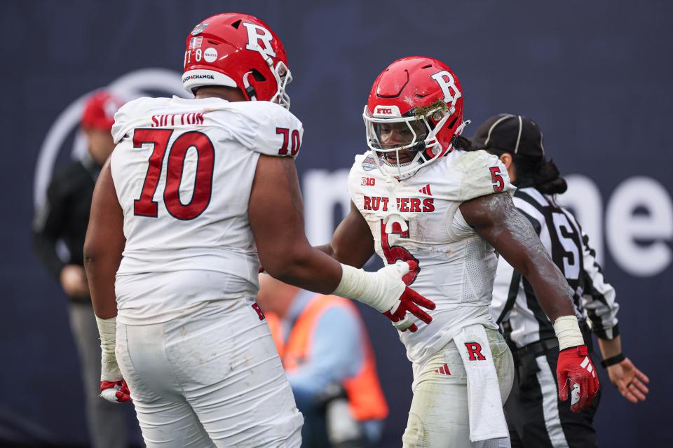 Dec 28, 2023; Bronx, NY, USA; Rutgers Scarlet Knights running back Kyle Monangai (5) celebrates his touchdown run with offensive lineman Reggie Sutton (70) during the first half of the 2023 Pinstripe Bowl against the Miami Hurricanes at Yankee Stadium. Mandatory Credit: Vincent Carchietta-USA TODAY Sports