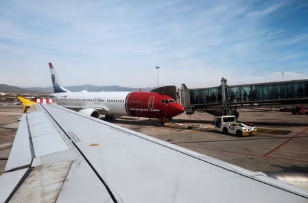 FILE PHOTO: Passengers walk towards a Norwegian aircraft next to a Vueling aircraft before taking off from Malaga-Costa del Sol airport in Malaga