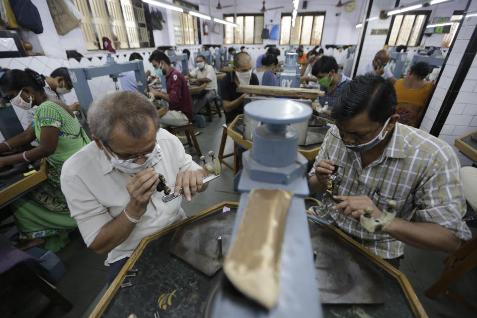 Numerosos obreros utilizan mascarillas por la pandemia de coronavirus en un taller de tallado diamantes en Ahmedabad, India, el sábado 4 de julio de 2020. (AP Foto/Ajit Solanki)