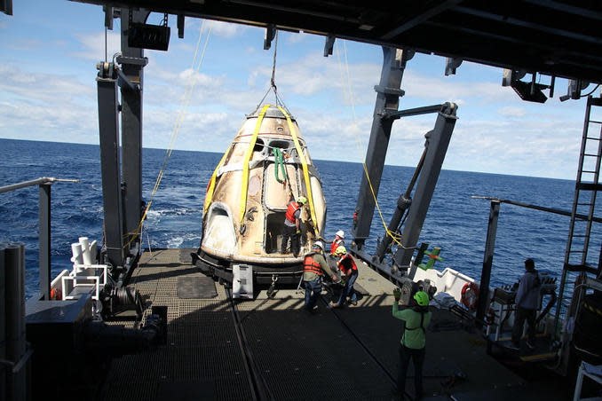 Slightly scorched after a successful unpiloted 2019 test flight, a Crew Dragon is hauled aboard a SpaceX recovery ship in the Atlantic Ocean. For piloted missions, the astornauts will stay inside the capsule until it is safely aboard the recovery ship. / Credit: SpaceX