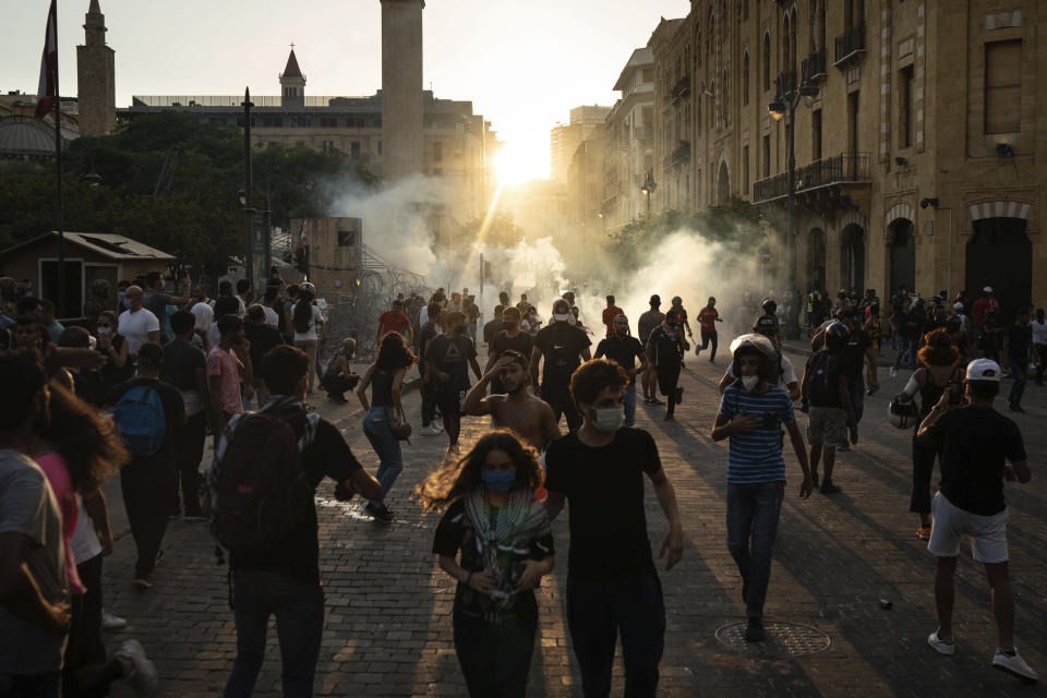 Demonstrators run from tear gas fired by police near the parliament building during a protest against the political elite and the government following last Tuesday's deadly explosion at the Beirut port which devastated large parts of the capital, in Beirut, Lebanon, Sunday, Aug. 9, 2020. (AP Photo/Felipe Dana)