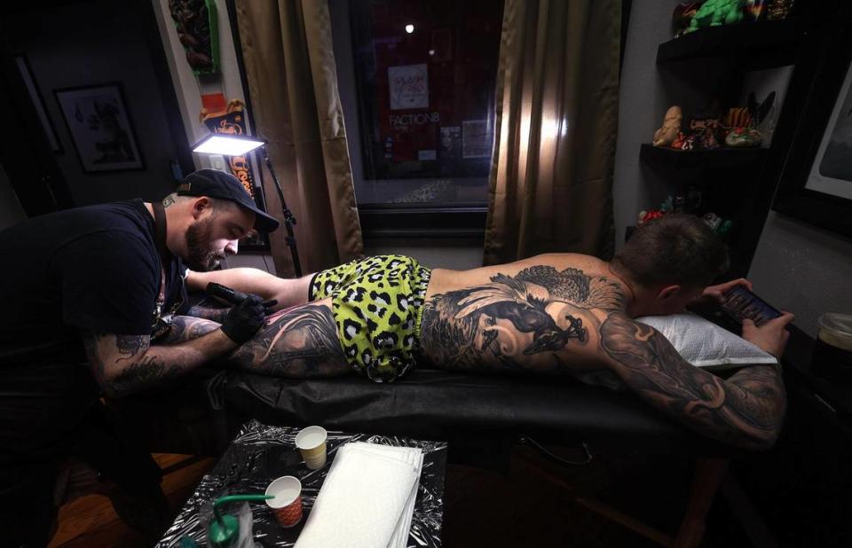 Scott Prather tatúa a Xander Fallek en su estudio privado de tatuajes de Fort Worth, el lunes 27 de marzo de 2023. Fallek, quien vive en Tulsa, Ok, acude con Prather desde agosto de 2020 y está cerca de completar un diseño de tatuaje que cubrirá el lado derecho de su cuerpo.