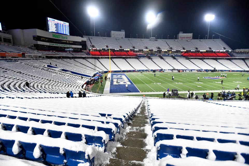 Snow covers the seats at Highmark Stadium as players conduct warmups before the Dec. 17 game between the Buffalo Bills and the Miami Dolphins in Orchard Park, N.Y.