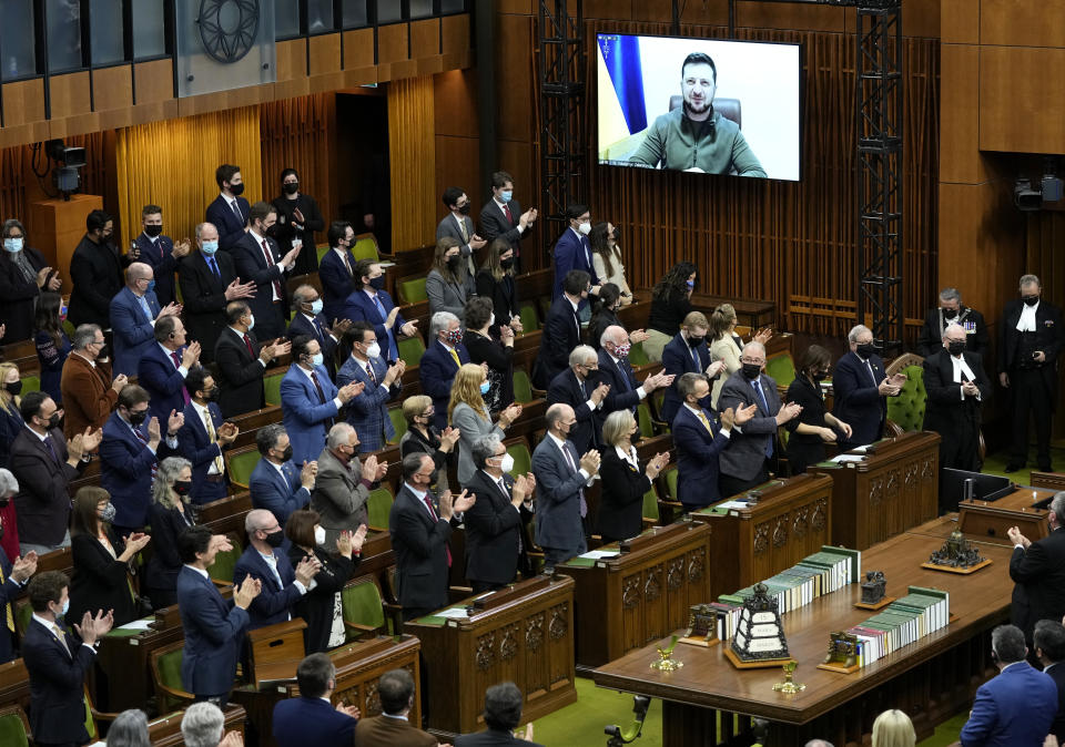 Ukrainian President Volodymyr Zelenskyy receives a standing ovation as he appears via videoconference to make an address to Parliament, in the House of Commons on Parliament Hill in Ottawa, on Tuesday, March 15, 2022. (Adrian Wyld /The Canadian Press via AP)