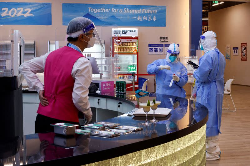 Workers wearing PPE sample the environment for virus detection at a restaurant inside the Main Press Centre, in Beijing