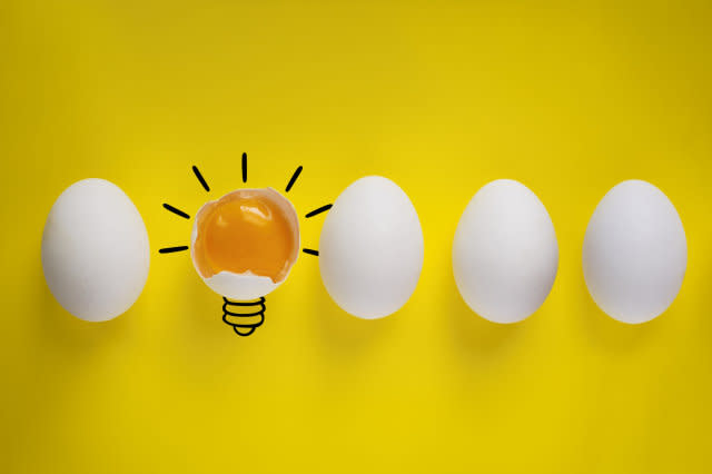 Four whole eggs and one broken egg on yellow background