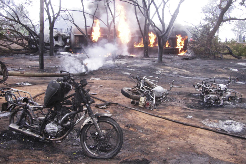 CORRECTING TO PETROL TANKER - Destroyed motorbikes and debris litter the scene as a petrol tanker burns in the background, Saturday, Aug. 10 2019, in Morogoro, Tanzania.  A damaged tanker truck exploded in eastern Tanzania Saturday as people were trying to siphon fuel out of it, killing at least 62, in one of the worst incidents of its kind in the East African country. (AP Photo)