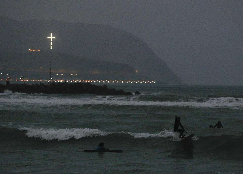 A surfer rides a wave at Makaha beach in Lima, Peru, as darkness falls Thursday, July 25, 2019. Today, dozens of schools teach tourists from across the world how to ride waves at beaches with Hawaiian names in Lima's Miraflores district, while professional surfers from across the Americas prepare to compete when the sport is featured for the first time in the Pan American Games in the Peruvian capital.(AP Photo/Rebecca Blackwell)