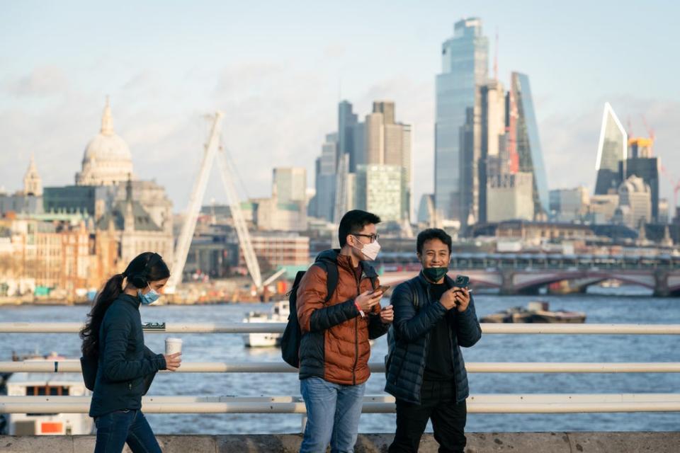 People wearing face masks cross Waterloo Bridge, London, after Prime Minister Boris Johnson announced that Plan B measures across England will be scrapped (Dominic Lipinski/PA) (PA Wire)