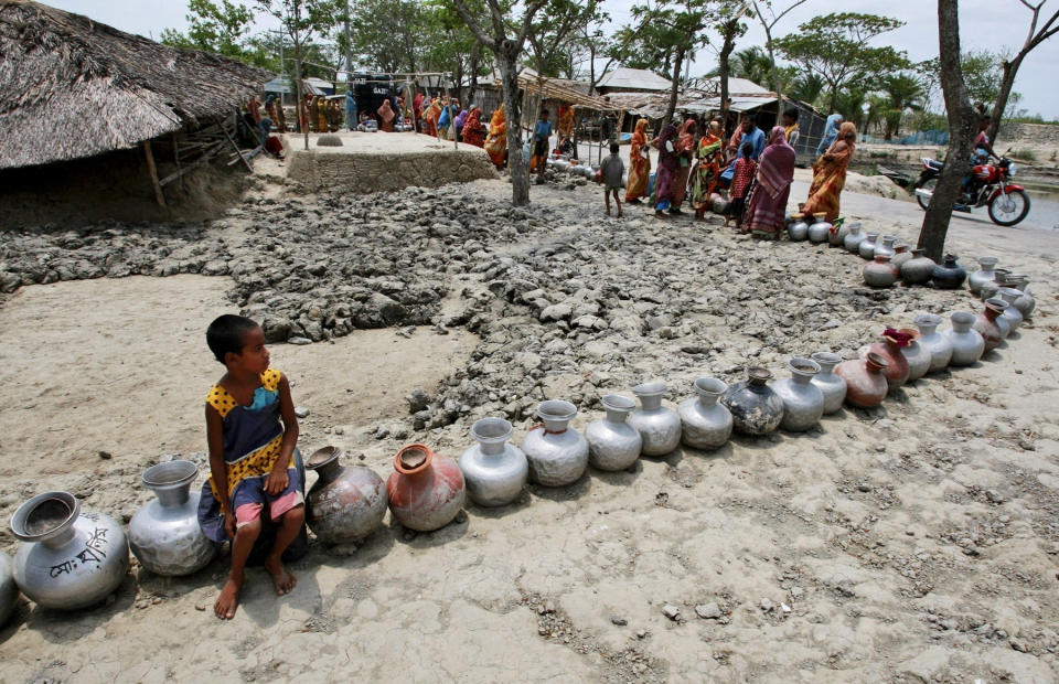 FILE - In this photo taken Friday, May 14, 2010, a girl sits on a vessel as she waits with others in a queue for water supplied by tankers at an area affected by last year's cyclone Aila in Nildumur, Satkhira district, about 176 kilometers (110 miles) southwest of the capital Dhaka, Bangladesh. Bangladesh plans to present its “climate prosperity plan” aimed at mitigating the effects of global warming on economic development at the forthcoming U.N. climate talks in Glasgow, Bangladeshi climate officer Abul Kalam Azad said in an interview with The Associated Press on Friday, Oct. 22, 2021. With most of its 160 million people tightly packed into low-lying areas along the Bay of Bengal, Bangladesh is considered especially prone to flooding, extreme weather and the loss of farmland to rising ocean levels. (AP Photo/Pavel Rahman, File)