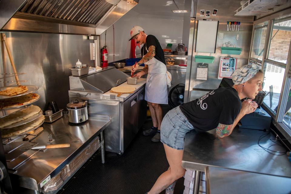 Chase Gilroy and Jess McAtee, owners of Flour-ish Comfort Food Truck, prepare pizzas Saturday.