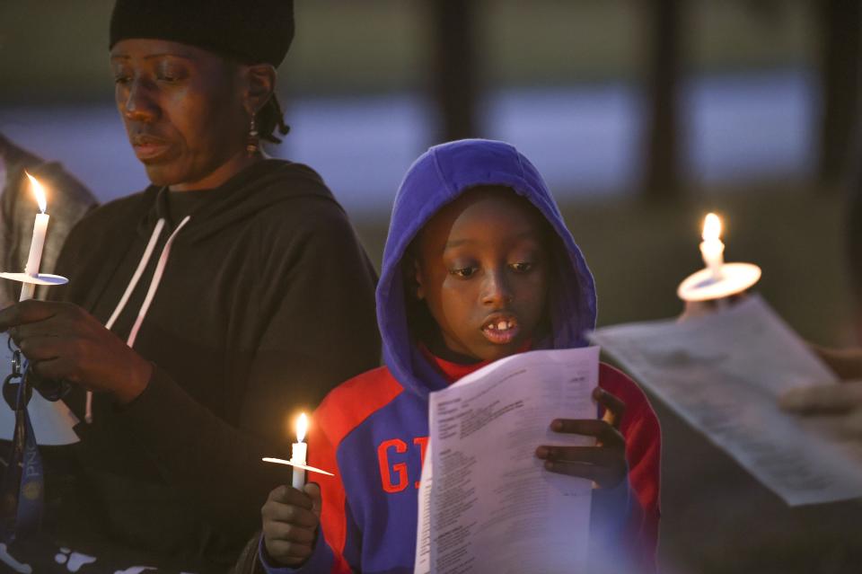 Abraham Reed, 11, of Fort Pierce, participates in a prayer vigil at the corner of North 13th Street and Avenue M with his mother (left) and around 18 others on Tuesday, Jan. 17, 2023, in Fort Pierce. Pastor Richard Cox, of Trinity Lutheran Church, lead the group in song and prayers during the vigil for those who were affected by the mass shooting during a Martin Luther King Jr. Day celebration and car show on Monday evening at Ilous Ellis Park.  "I do kind of feel bad for the people who lost loved ones yesterday," Abraham said. 